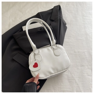 Dettaglio borsa bianca con texture litchi, anelli argentati e ciondolo a cuore