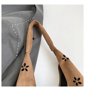 Detail of laser-cut petal patterns and rounded stitched handles on suede tote bag