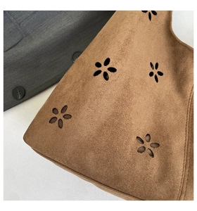 Close-up of brown suede shoulder bag featuring laser-cut floral patterns and texture