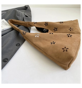 Detail of laser-cut flower patterns on brown suede tote bag with wide shoulder strap