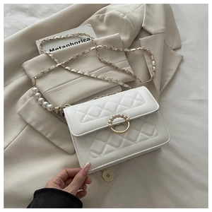 Detail einer weißen Stepptasche mit goldenem Perlenverschluss und Lederkette
