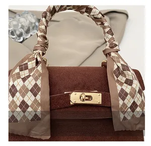 Detail of golden metal swivel lock and corduroy texture on dark brown handbag