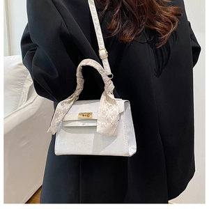 Close-up of white leather Kelly bag with litchi texture and silk scarf wrapped handle