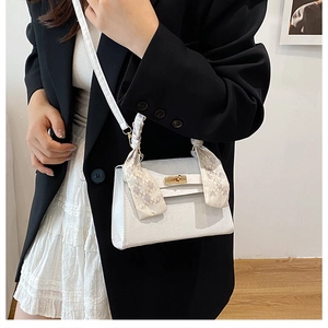 Detail of white mini Kelly bag with elegant geometric scarf-wrapped handle and gold lock
