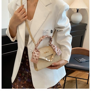 Detail of elegant champagne beige handbag with silk scarf handle and gold twist lock