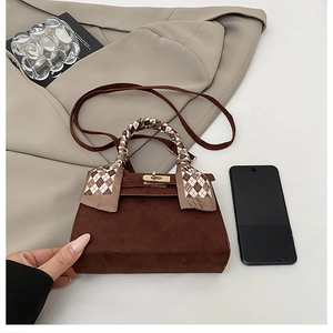 Close-up of brown textured handbag with gold twist-lock and plaid scarf handle detail