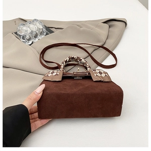 Detailed macro of dark brown suede Kelly bag featuring a checkered scarf wrapped handle