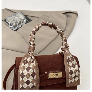 Close-up of brown corduroy handbag with plaid silk scarf and gold metal turn-lock