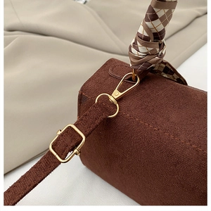 Detail of dark brown suede handbag featuring a decorative checkered scarf and gold hardware
