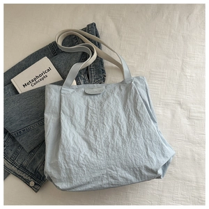 Vue à plat du cabas plissé bleu clair avec patch FASHION sur une surface texturée