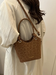 Brown leopard print bucket bag with gold hardware worn with a beige trench coat