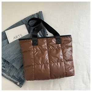 Close-up of brown quilted puffer tote bag with wide black strap and waterproof texture