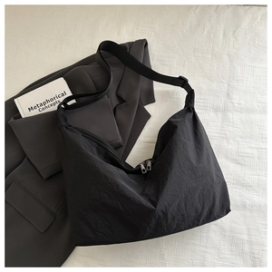 Detail of black minimalist hobo bag featuring crinkled texture and wide shoulder strap
