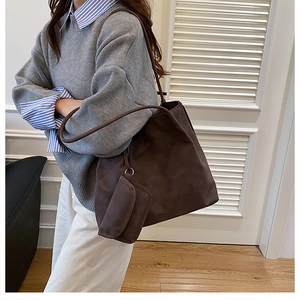 Detail of a large chocolate brown suede tote bag with matching pouch on model