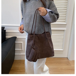 Detail of dark brown matte leather tote bag with small matching accessory on shoulder