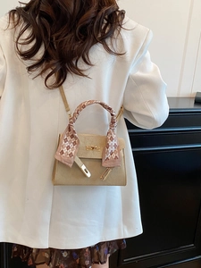 Beige matte leather Kelly bag with silk scarf handle on a white blazer model