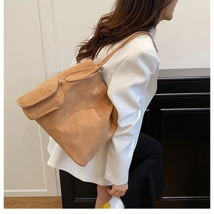 Close-up of a large brown vintage tote bag with thin straps and a matching mini pouch