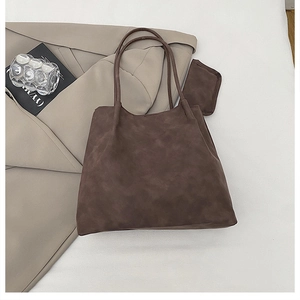 Detail of dark brown suede tote bag with slim straps and matching mini pouch