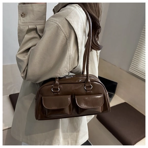 Detail view of a dark brown glossy shoulder bag with dual front flap pockets