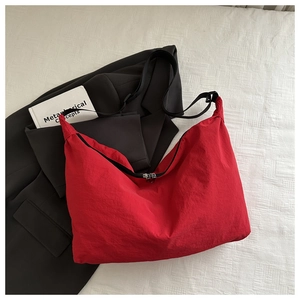 Detail of red nylon tote bag featuring silver zipper and contrast black shoulder strap