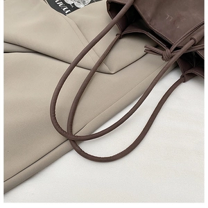 Close-up of a coffee brown tote bag with slim handles and a unique knotted tie detail
