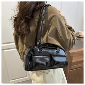 Detail of glossy black shoulder bag featuring dual front flap pockets and silver hardware
