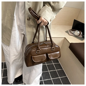 Detail of retro brown leather handbag featuring dual front pockets and shoulder straps
