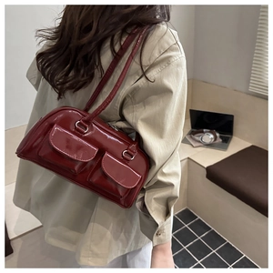 Detail of dark red patent leather shoulder bag featuring two front pockets and silver rings