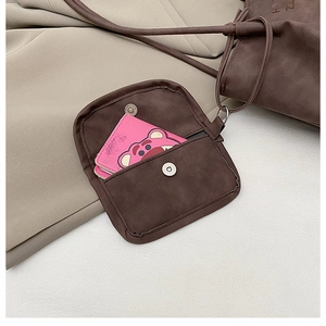 Detail of dark brown tote bag showing the magnetic buckle pouch and plush charm accessory