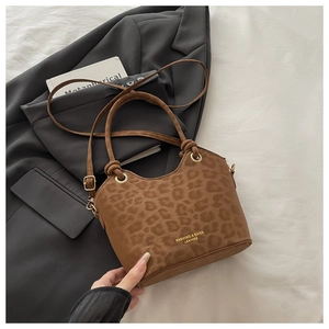 Detail of leopard print bucket bag with gold hardware resting on a grey blazer