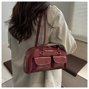 Detail of dark red patent leather Boston bag with glossy finish and double pockets