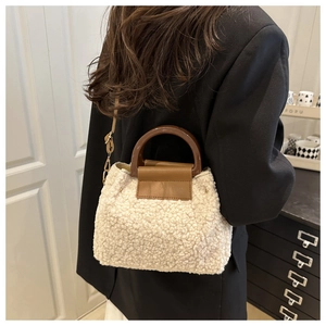 Gros plan du sac bandoulière en fausse fourrure beige avec poignée en cuir marron