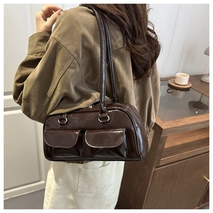 Detail of a dark chocolate glossy shoulder bag with twin front flap pockets and zipper