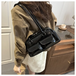 Detail of black glossy shoulder bag with double front pockets and retro bowling style