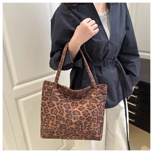 Detailed view of large leopard print tote bag worn over the shoulder by a model