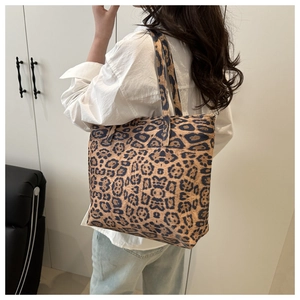 Detail shot of leopard print tote bag with shoulder strap worn by a model in casual attire