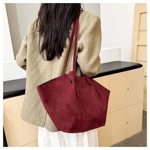 Close-up of large burgundy suede tote bag with shoulder straps shown on a model