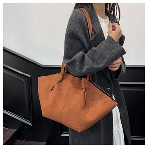 Close-up of caramel suede tote bag with knotted strap detail on wool coat