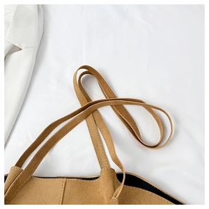 Detail of tan suede tote bag featuring dual shoulder straps and smooth black lining