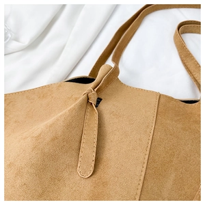 Close-up of camel suede tote bag showing delicate knot design and fine stitching details