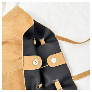 Detailed close-up of brown suede tote bag with magnetic snaps and black leather lining