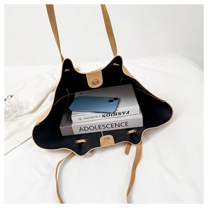 Top view of large tan suede tote bag with magnetic closure holding books and phone