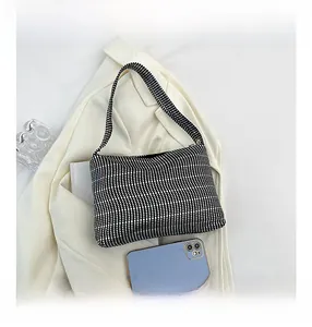 Detailed view of checkered rhinestone underarm bag showing size comparison with a smartphone