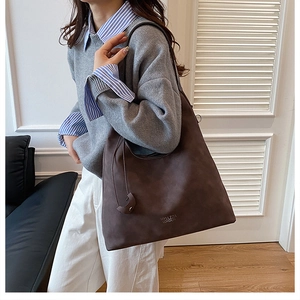 Detail of a large dark brown suede tote bag with embossed brand logo for women