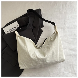 Macro view of beige nylon hobo bag showing wrinkled texture and black crossbody strap