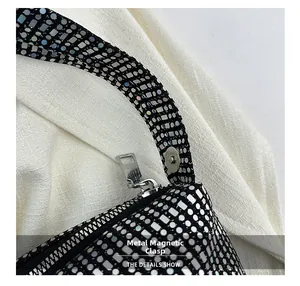 Detail of hardware magnetic snap and smooth zipper on black sequin canvas shoulder bag