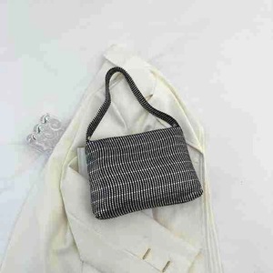Detail of checkered rhinestone shoulder bag on white blazer with high-end party aesthetic