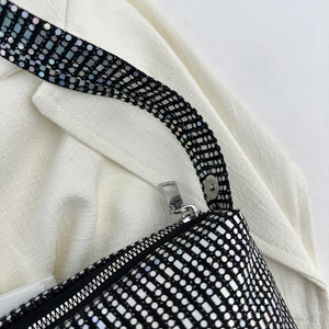 Detailed close-up of a black canvas bag with shiny silver sequins and metal zipper