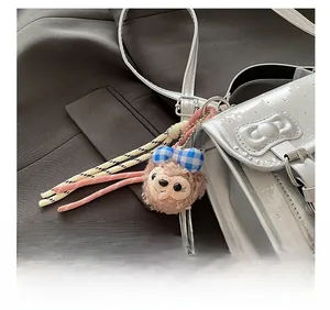 Close-up of plush ShellieMay charm with blue plaid bow on a silver crossbody bag