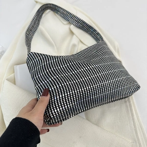 Close-up of a silver sequined checkerboard baguette bag with a glossy metallic finish